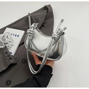 Detail of silver metallic shoulder bag featuring a knotted handle and pearl pendant