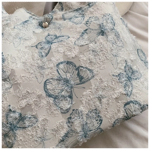 Close-up of fringe texture and blue butterfly print on a summer tote bag with metal button