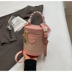 Detailed view of pink bucket bag with woven texture and decorative scarf handle