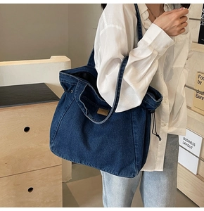 Detail der blauen Denim-Tragetasche mit braunem Lederpatch und Kordelzugverschluss
