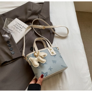 Detailed close-up of light blue leather handbag with blue butterfly prints and cute dog charm