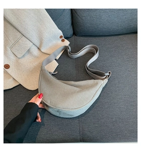 Detail of light grey corduroy crescent bag showing soft ribbed texture and adjustable strap