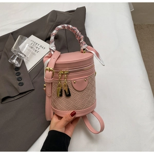 Detail of pink bucket bag featuring woven texture and silk scarf wrapped handle