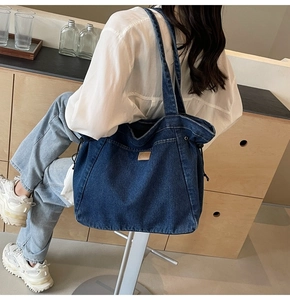Detail der großen marineblauen Denim-Einkaufstasche mit Kordelzug und Leder-Patch