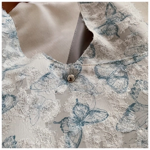 Detailed macro view of embroidered tote bag with blue butterfly patterns and white fringe