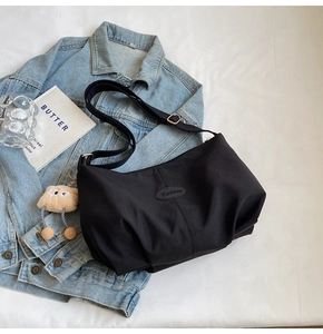 Close-up of black pleated tote bag with adjustable strap and cute plush charm