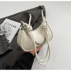 Detail of off-white crescent bag with pebble leather, knot handles, and silver chain pearl