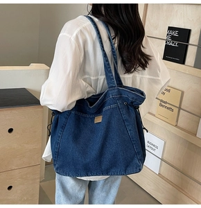 Nahaufnahme einer blauen Denim-Tragetasche mit seitlichen Kordelzügen und Lederetikett