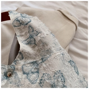 Macro detail of blue butterfly embroidery and metal button on semi-transparent lace tote bag