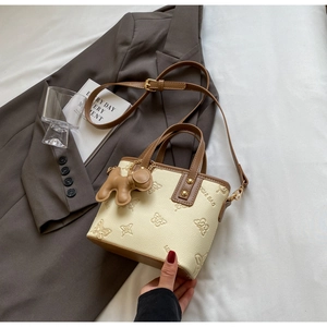 Detailed butterfly embossed cream leather bag with brown trim and cute puppy charm