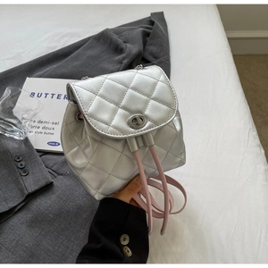 Détail macro du mini sac à dos argenté matelassé avec finition métallique et fermoir rotatif