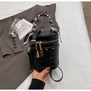 Detail of black woven bucket bag with silk scarf handle and golden hardware accents