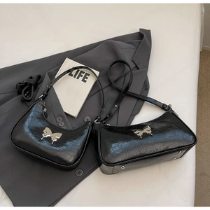 Dettaglio della borsa in pelle cerata nera con fibbia metallica a forma di fiocco argento