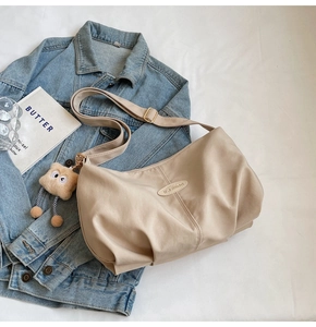 Detail of pleated beige tote bag with iFashion logo and cute plush charm pendant