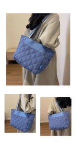 Detail view of blue quilted tote bag featuring a diamond pattern and logo patch