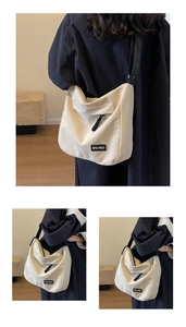 Detail of off-white canvas crossbody bag with black adjustable strap and brand label