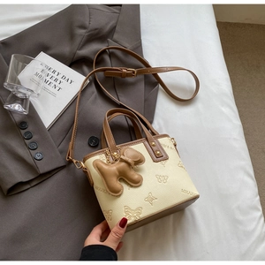 Detail of off-white tote bag featuring butterfly prints and a cute dog charm