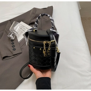 Detail of black woven bucket bag with silk scarf handle and gold chain accents