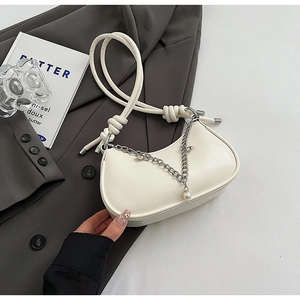 Detail of creamy white crescent hobo bag with knotted strap and silver chain pearl charm