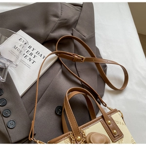 Close-up of a vintage beige and brown patchwork bucket bag on a grey suit jacket
