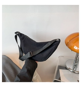 Detail of black corduroy crescent bag with adjustable strap and textured surface