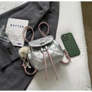 Détail du sac à dos argenté matelassé avec fermoir métal, brides roses et peluche