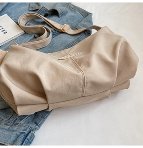 Close-up of beige pleated tote bag with soft texture and adjustable golden buckle