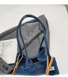 Detail of blue denim bucket bag with brown leather handles and smooth long straps