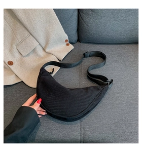 Detail of black corduroy crescent bag featuring adjustable strap and soft ribbed texture