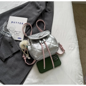 Détail du mini sac à dos matelassé argenté avec cordons roses et fermoir rotatif en métal
