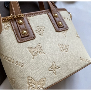Close-up of embossed butterfly pattern on beige textured leather with golden hardware