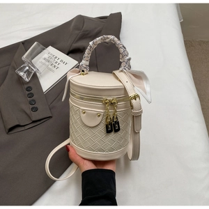Detail of woven texture and silk scarf handle on a beige bucket bag with gold accents