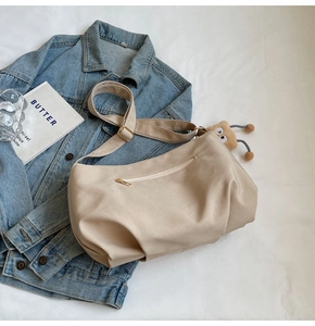 Detailed view of beige hobo bag back zipper pocket and plush eye-shaped charm