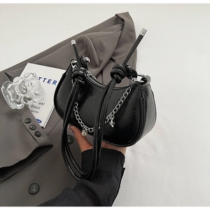 Detail of black glossy crescent bag with silver star charms and knot strap design