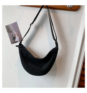 Close-up of black crescent dumpling bag with textured ribbed fabric and adjustable strap
