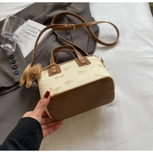 Detailed view of cream leather crossbody bag with brown trim and embossed butterfly pattern