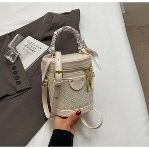 Detail of cream bucket bag with woven texture and decorative silk scarf handle