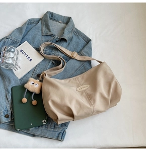 Detail of beige pleated tote bag with iFashion label and plush monster pendant