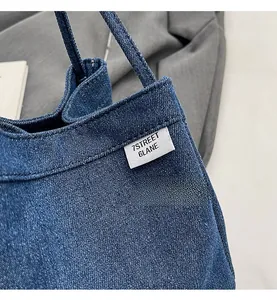 Close-up of blue denim tote bag showing twill texture and white woven brand label