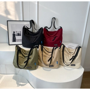 Detail shot of five casual nylon hobo bags in assorted colors on a minimalist display
