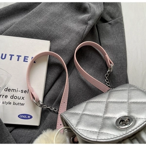 Détail du sac à dos argenté matelassé avec bandoulière chaîne et pompon blanc décoratif