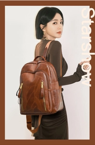 Detail of dark brown faux leather backpack featuring leaf-shaped stitching and gold zippers