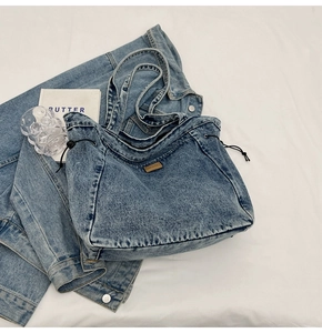 Detailansicht der blauen gewaschenen Denim-Tote-Bag mit schwarzem Kordelzug und Lederetikett