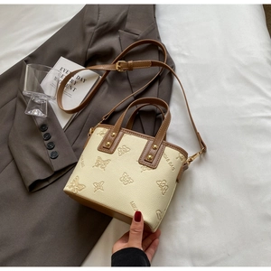 Detail of off-white leather bucket bag with butterfly embossing and brown handles