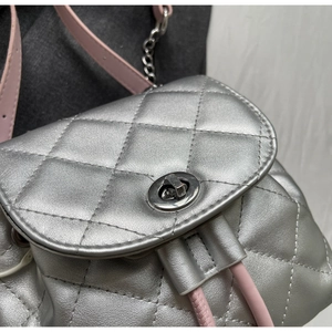 Détail de la texture matelassée argentée et du fermoir métallique du mini sac à dos