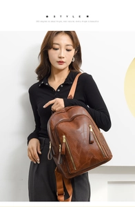 Detail of brown PU leather backpack with leaf stitching and gold zippers on model