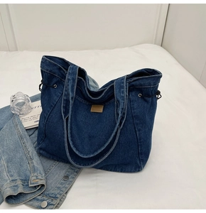 Detail der blauen Denim-Tragetasche mit Leder-Patch und seitlichen Kordelzug-Details