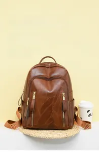 Detail of vintage embossed brown leather backpack featuring leaf patterns and multi-zippers