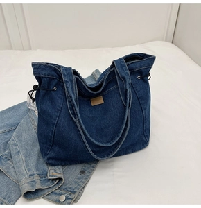 Detailansicht der dunkelblauen Denim-Tragetasche mit Lederpatch und Kordelzug-Detail