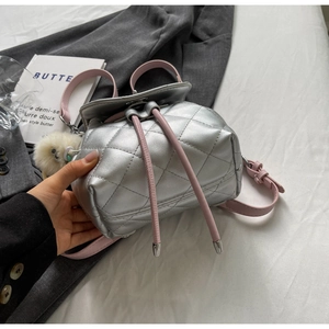 Vue détaillée du mini sac à dos matelassé argenté avec cordon rose et pompon blanc